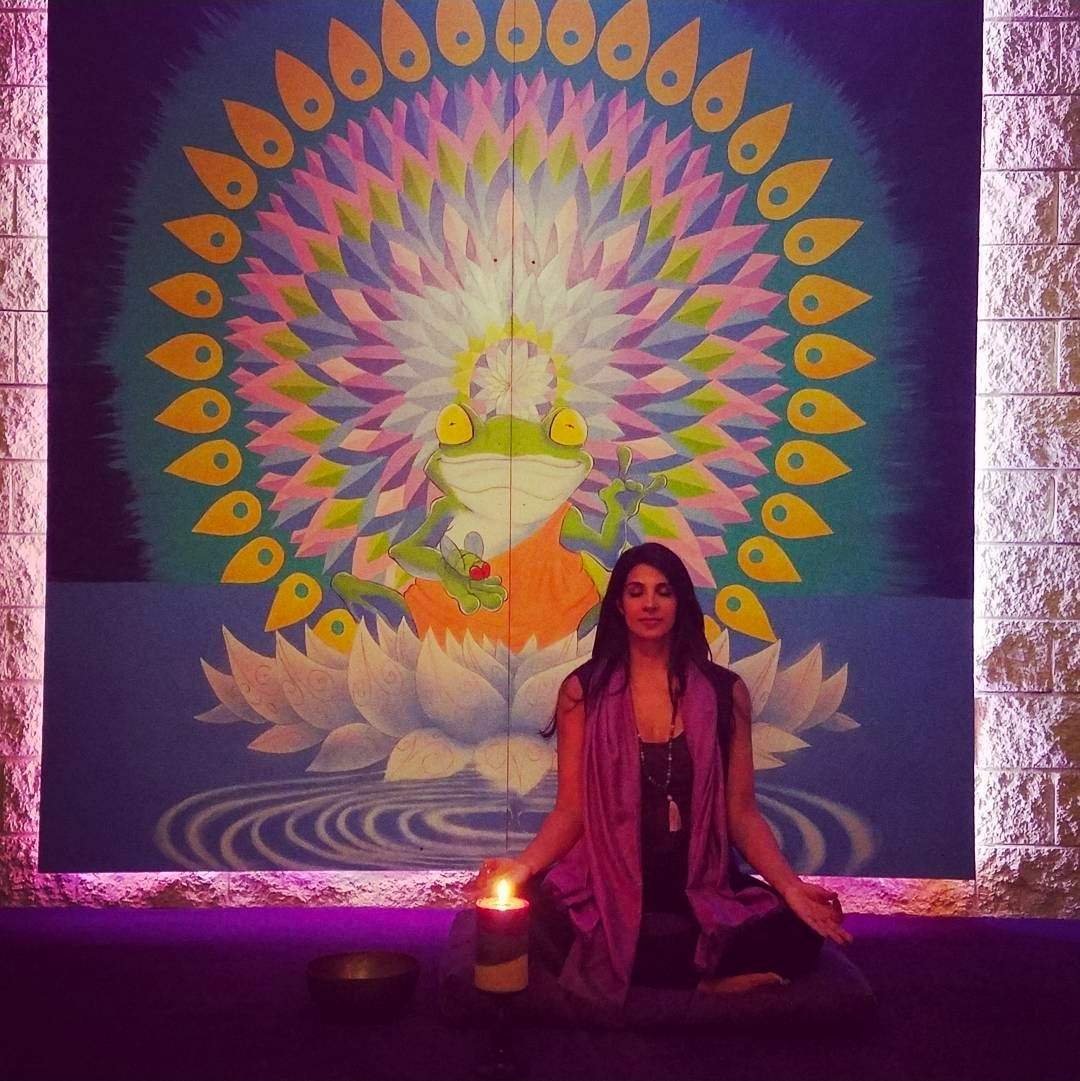 Jeena meditating with candles and mandala mural at JeeNamaste
